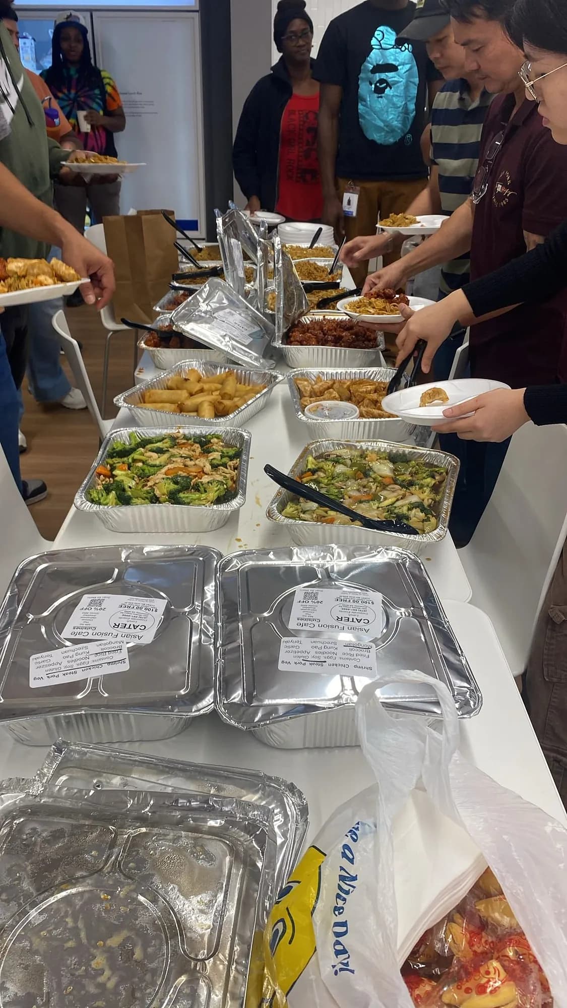 Office staff serving themselves from a catered lunch of foil trays