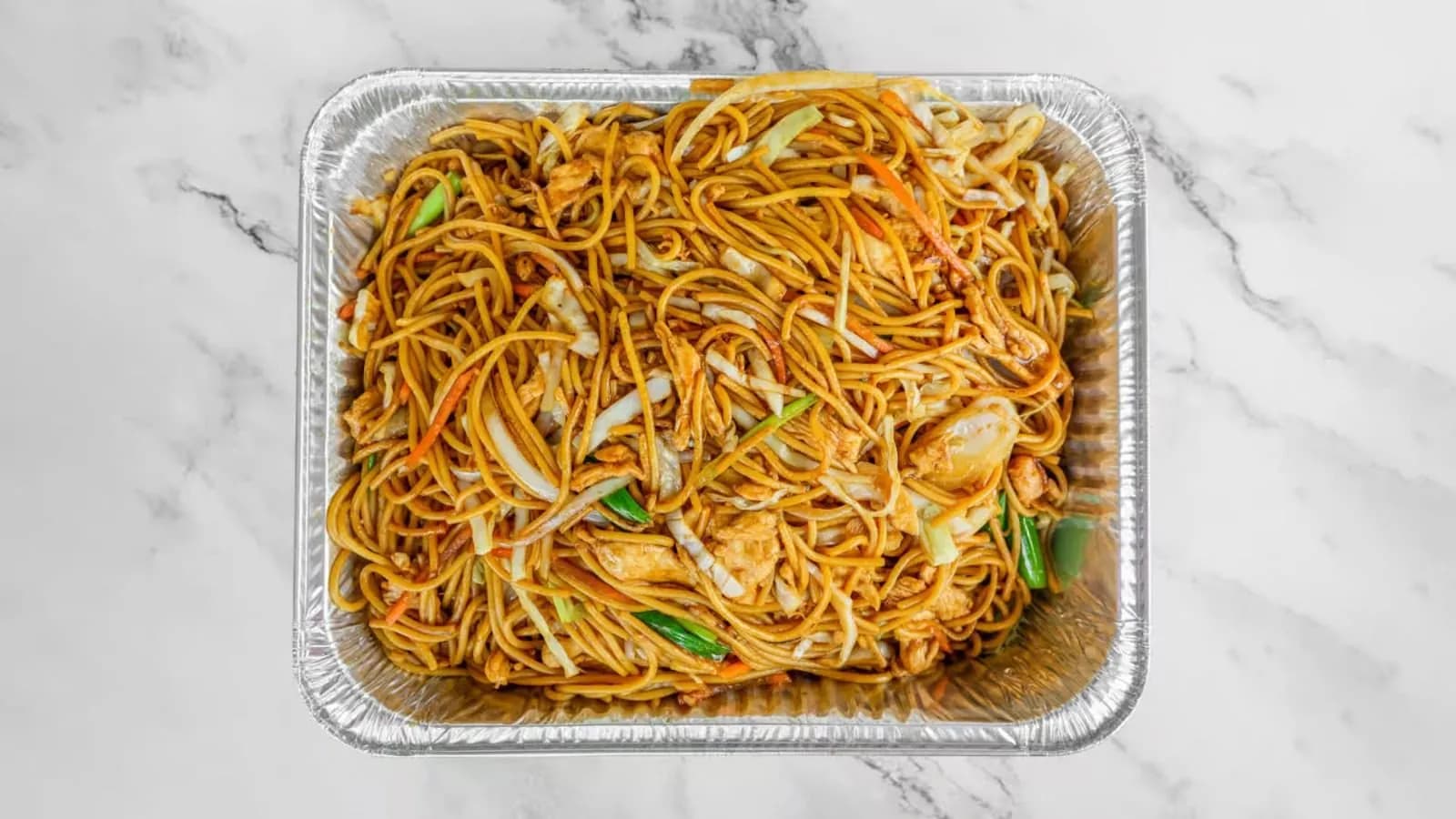 Catering tray of chicken lo mein on a marble counter